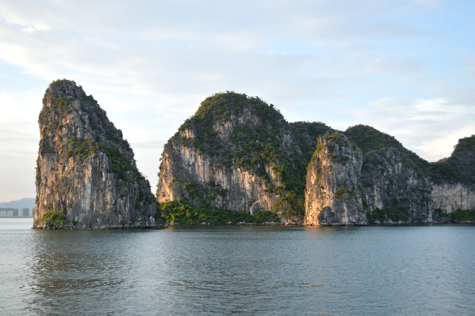 Limestone cliffs reflecting in calm water, Halong Bay