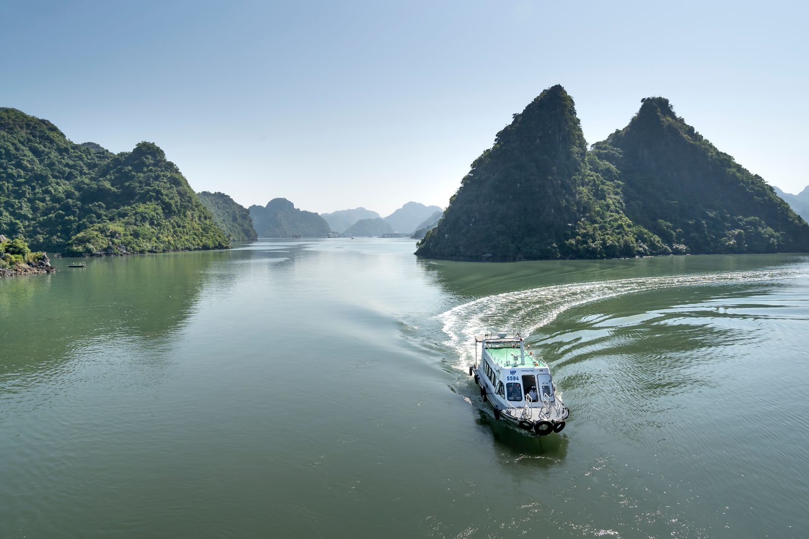 Ferry cruising through Halong Bay between limestone islands